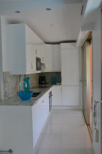 - une cuisine avec des placards blancs et un bol bleu sur le comptoir dans l'établissement Beau studio vu mer juan les pins, à Antibes