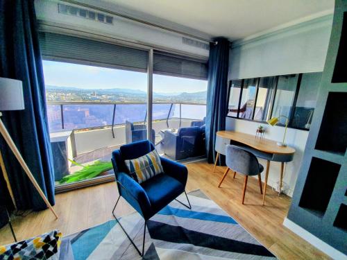 a living room with a blue chair and a table and a large window at Appartement T2 Prado Chanot Plage Marseille in Marseille