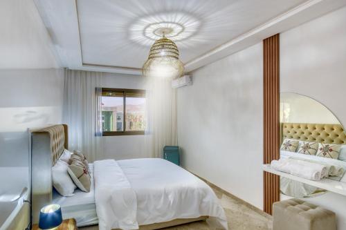 ein weißes Schlafzimmer mit einem Bett und einem Spiegel in der Unterkunft Élégance - Appartement de luxe au centre d'Agadir in Agadir