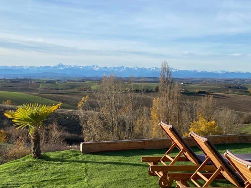 2 chaises en bois assises au-dessus d'un champ vert dans l'établissement Villa 15 personnes - Piscine - Jacuzzi - Clim - Bar - Billard - Cinéma - Vue Panoramique, à Esperce
