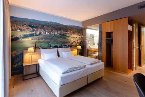 ein Schlafzimmer mit einem großen Bett und einem Gemälde an der Wand in der Unterkunft Hotel Stainzerhof in Stainz