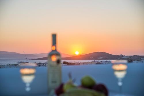 a view of the sunset from a table with wine glasses at Cycladic Islands Hotel & Spa in Agia Anna Naxos