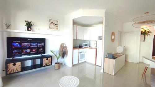 een woonkamer met een televisie en een keuken bij Residential Golf Park - Casa Prezi in San Miguel de Abona