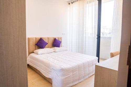 a bedroom with a white bed with purple pillows at Zayn villa in Mount Lavinia
