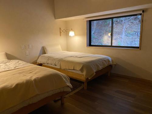 2 camas en una habitación con ventana en wine& stay Shinyashiki, en Nishimura