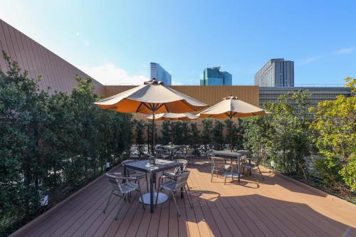 two tables and chairs with umbrellas on a deck at Dormy Inn Premium Ginza - Natural Hot Spring in Tokyo