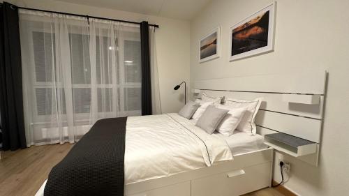 1 dormitorio con 1 cama blanca grande y ventana en Pearl - new and cosy apartment close to Center, en Riga