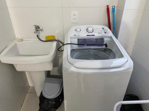 uma máquina de lavar roupa e um lavatório numa pequena casa de banho em Apartamento próximo ao Pão de Açúcar e centro em Limeira