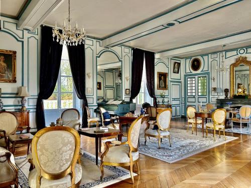 a living room with chairs and tables and a chandelier at Château des Feugerets in Bellême