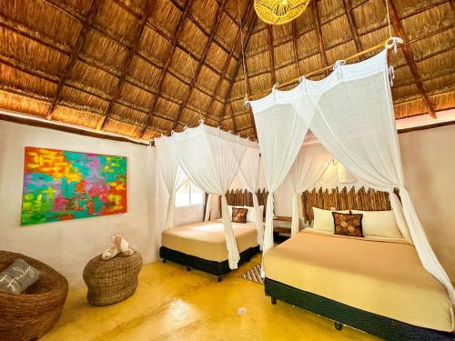 a bedroom with two beds and a straw roof at Alito Tulum Hotel in Tulum