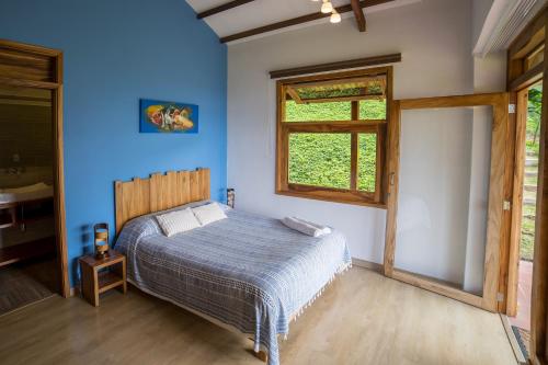 a bedroom with a bed with blue walls and a window at Ecoresort Gran Azul in Salento