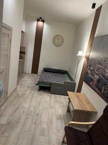 リヴィウにあるApartments Kulisha 14 Centre lvivのベッド、テーブル、時計が備わる客室です。