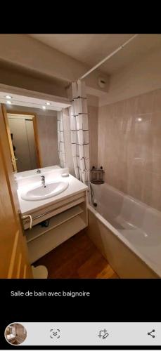 une salle de bain avec un lavabo, une baignoire et un miroir dans l'établissement T2 au pied des pistes, à Puy-Saint-Vincent