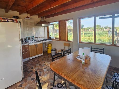 a kitchen with a wooden table with chairs and a refrigerator at Hostal Casa los Duendes in San Pedro de Atacama