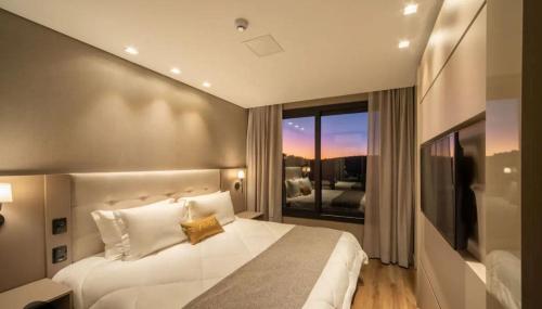 a bedroom with a large white bed and a window at CHATEAU DU GOLDEN in Gramado