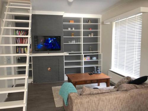 a living room with a couch and a tv at Heerlijk halfvrijstaande woning in Hierden