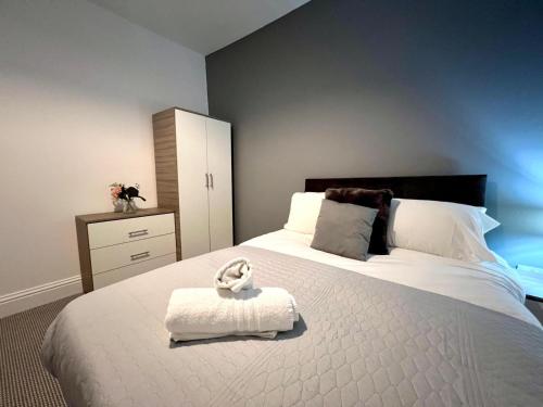 a bedroom with a large white bed with a white towel at Luxury Victorian House Sleeps 6 - 11 Guests JLR, Trades, Relocations & Hs2 Welcome Wheelchair Accessible Home FREE Faster WIFI & PARKING in Coventry