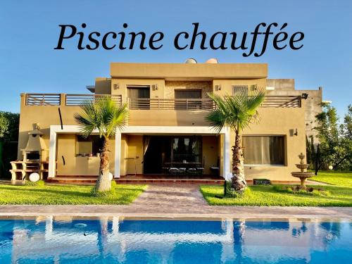a house with palm trees in front of a swimming pool at Villa Haitam Marrakech in Oubadine