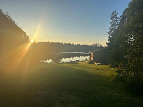 a view of a house and a lake with the sun setting at Villa Lillebo in Bengtsfors