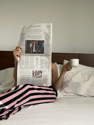 una persona tirada en la cama leyendo un periódico con una taza de café en Grand Hotel Florencia, en Florencia