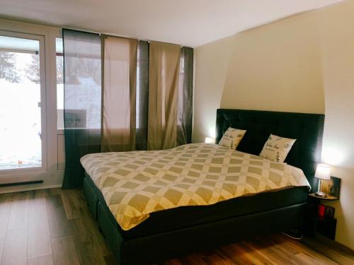 a bedroom with a bed and a large window at Family Apartment MiniGlück in Sankt Englmar