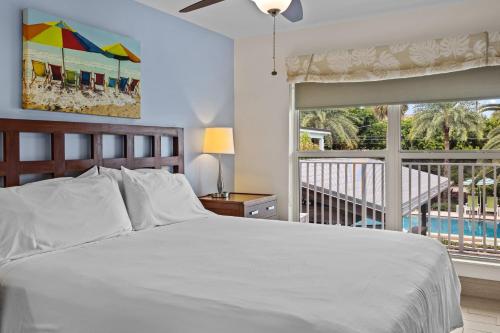 a bedroom with a white bed and a balcony at Sun Dek Beach House in Boynton Beach