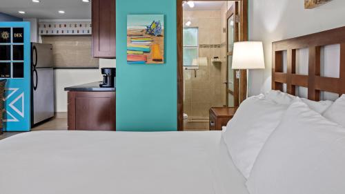 a bedroom with a white bed and a kitchen at Sun Dek Beach House in Boynton Beach