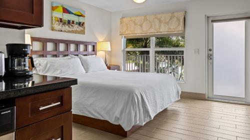 a bedroom with a white bed and a kitchen at Sun Dek Beach House in Boynton Beach
