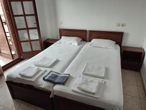 un grande letto con lenzuola bianche e asciugamani sopra di Ξενώνας Φωτεινη a Ouranoupoli
