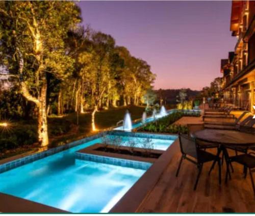 a swimming pool with a table and a fountain at CHATEAU DU GOLDEN in Gramado