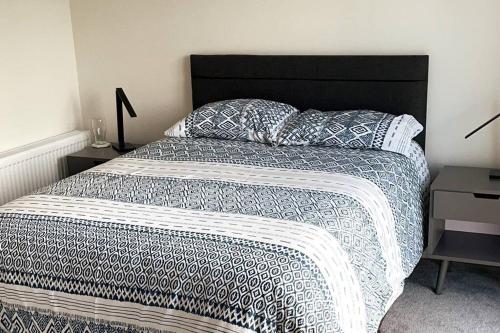 a bed with a black and white comforter and pillows at Salt Life Portstewart in Portstewart