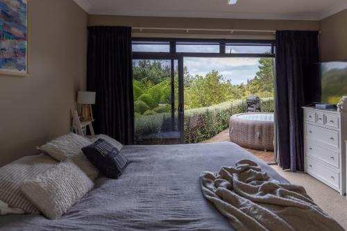 a bedroom with a large bed and a large window at TAIRUA SLICE OF PARADISE! in Tairua