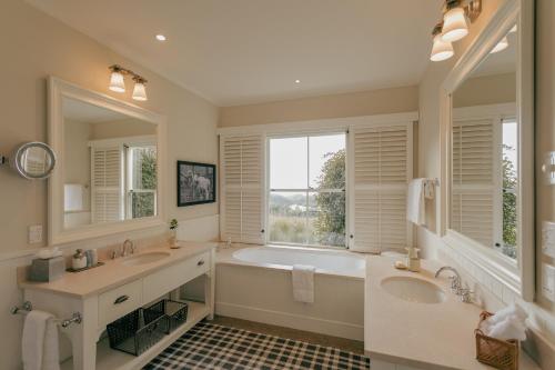 baño con 2 lavabos, bañera y ventana grande en Rosewood Cape Kidnappers en Te Awanga