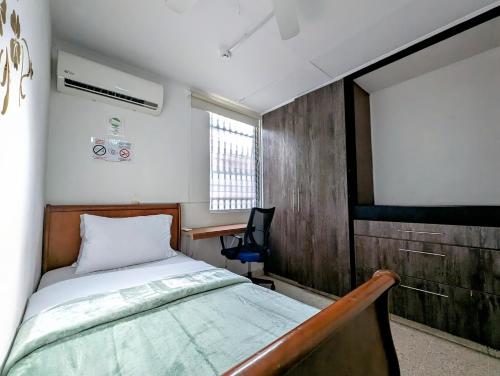 a bedroom with a bed and a desk and a window at Hostal Yoha in Panama City