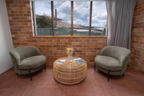 two chairs and a table in a room with a brick wall at All Seasons Motel Armidale in Armidale