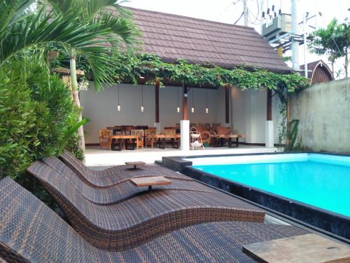 ein Pool mit Liegestühlen und ein Restaurant in der Unterkunft De, dalam secret nature in Ubud