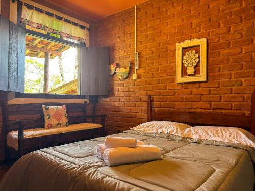 een slaapkamer met een bed en een bakstenen muur bij Alecrim Pousada in Conceição da Ibitipoca