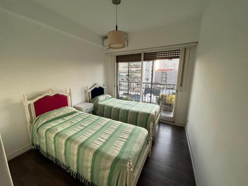 um pequeno quarto com 2 camas e uma janela em Tu departamento en Vicente López em Vicente López