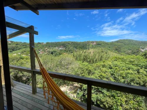 a hammock on a deck with a view of the mountains at Pousada Vale da Magia in Praia do Rosa
