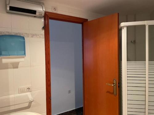 a bathroom with a toilet and a wooden door at Apartamento Diagonal in Nules