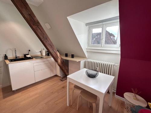 una pequeña cocina con una mesa blanca y una ventana en Les toits de Gutenberg, en Estrasburgo