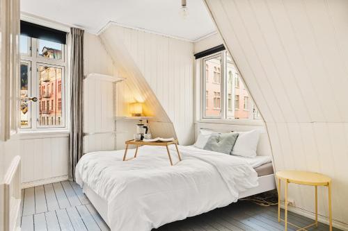 1 dormitorio blanco con 2 camas y mesa en Live in historic building - View to Bryggen, en Bergen