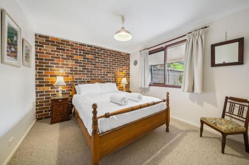 a bedroom with a bed and a brick wall at Rosella Retreat in Blackheath