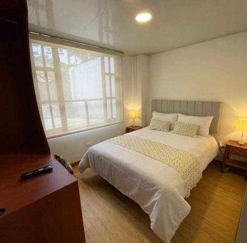 ein Schlafzimmer mit einem weißen Bett und einem Fenster in der Unterkunft VILLA DE MOYA HOTEL MONGUI in Monguí