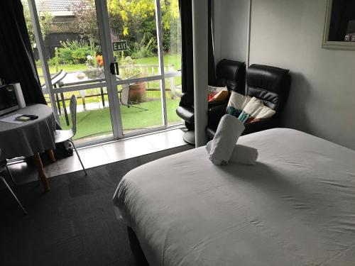 a bedroom with a bed and a chair and a window at Sandy Feet Accommodation in Christchurch