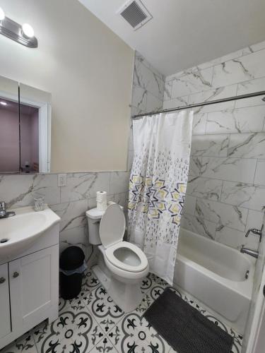 een witte badkamer met een toilet en een wastafel bij Pleasing 3BR Apt, Mins to NYC in Jersey City