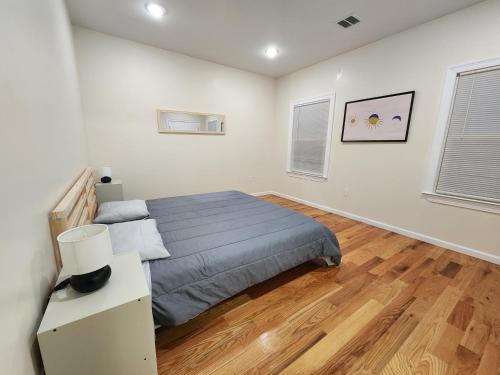 een slaapkamer met een bed en een houten vloer bij Pleasing 3BR Apt, Mins to NYC in Jersey City