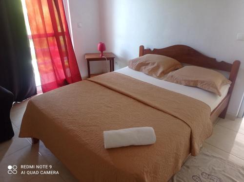 a bed with a brown blanket and a pillow on it at Recanto D'nha Fana in Porto Novo