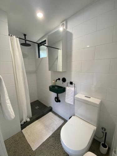 a white bathroom with a toilet and a sink at Central Gem in Dunsborough