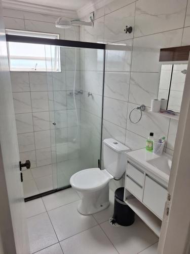 a bathroom with a toilet and a glass shower at Cobertura Guarujá in Guarujá